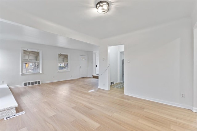 unfurnished living room with light wood-style flooring, visible vents, and baseboards