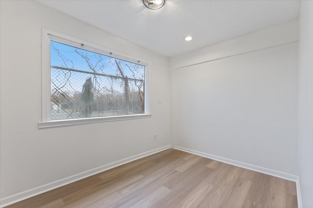 spare room with a textured ceiling, baseboards, wood finished floors, and recessed lighting