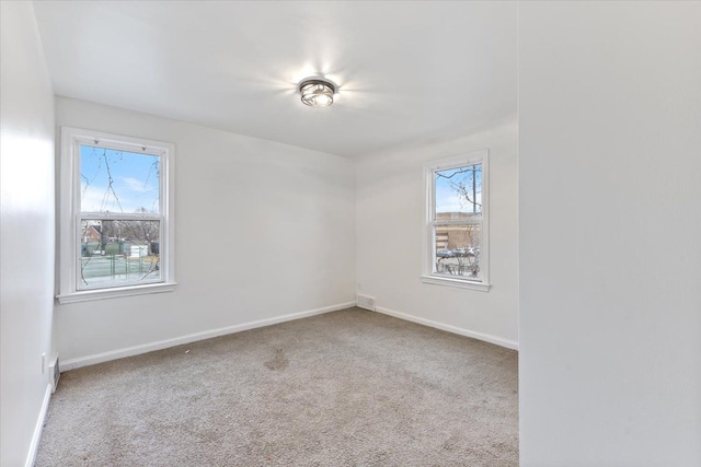 spare room featuring carpet flooring, a wealth of natural light, and baseboards