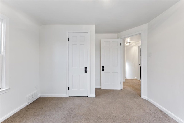 unfurnished bedroom with carpet flooring, visible vents, and baseboards