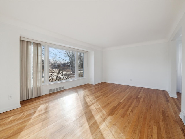 spare room featuring visible vents, light wood-style flooring, and baseboards