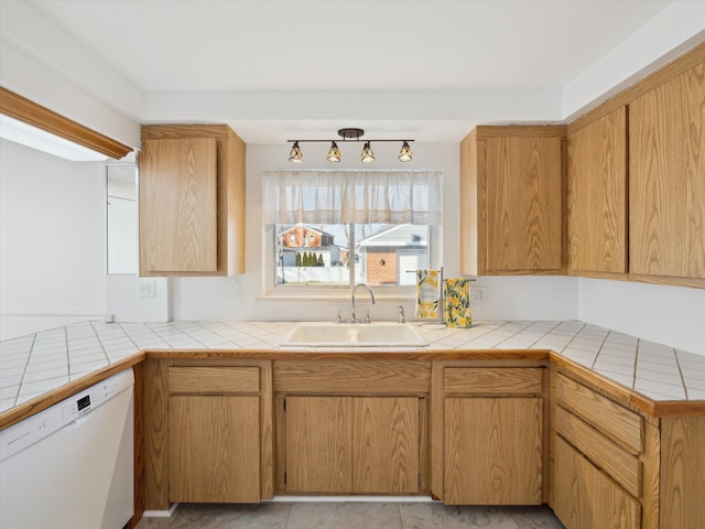 kitchen featuring tile countertops, a peninsula, white dishwasher, and a sink