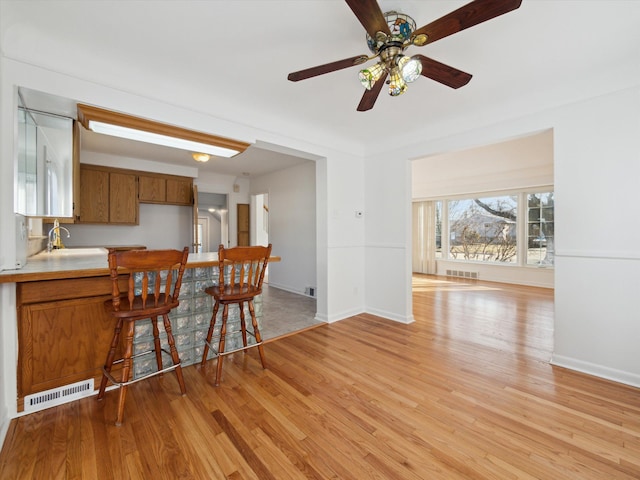 kitchen featuring brown cabinetry, light countertops, visible vents, and light wood finished floors