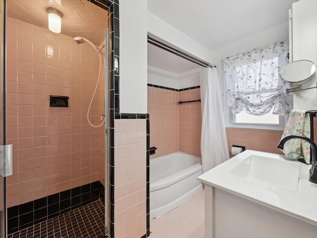 bathroom featuring tiled shower / bath combo, tile walls, and vanity