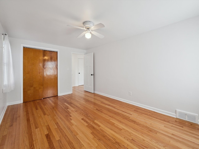 unfurnished bedroom with baseboards, visible vents, ceiling fan, light wood-type flooring, and a closet