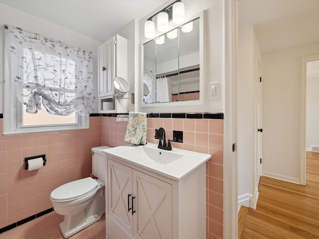 bathroom with tile walls, visible vents, toilet, vanity, and wood finished floors