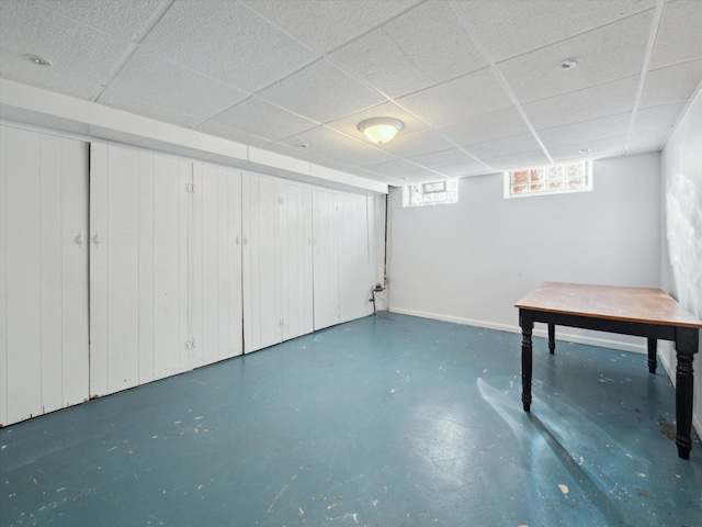 basement with baseboards and a drop ceiling