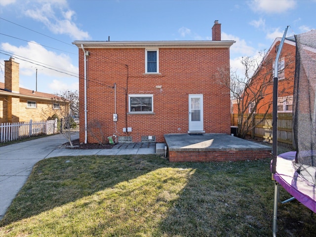 rear view of property featuring a patio area, brick siding, fence, and a lawn