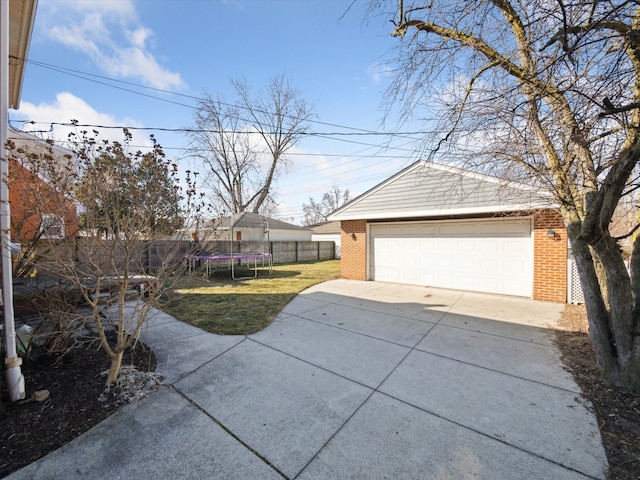 detached garage with a trampoline and fence