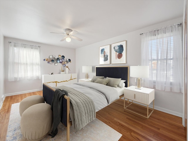 bedroom with a ceiling fan, multiple windows, baseboards, and wood finished floors