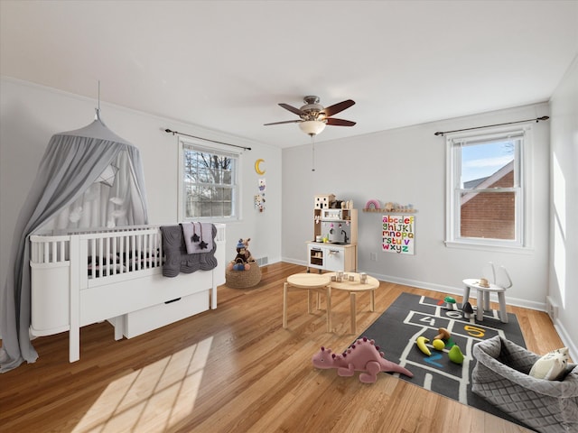 bedroom with a ceiling fan, baseboards, visible vents, and wood finished floors