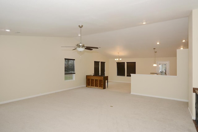 spare room with lofted ceiling, light colored carpet, baseboards, and ceiling fan with notable chandelier