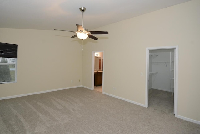 unfurnished bedroom with baseboards, a walk in closet, and light colored carpet