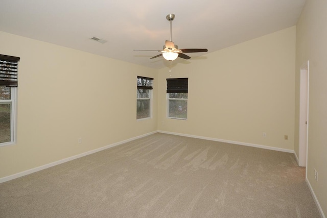 empty room featuring light carpet, plenty of natural light, and baseboards