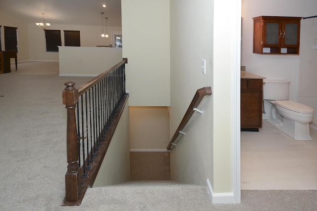 staircase with a chandelier and carpet