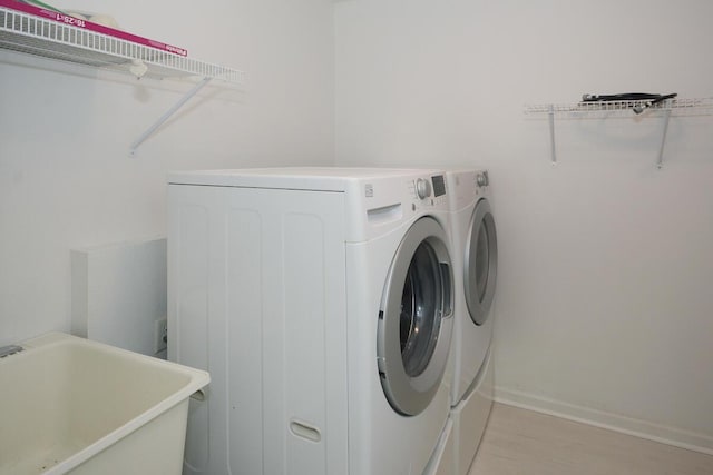 laundry area featuring a sink, laundry area, washing machine and clothes dryer, and baseboards