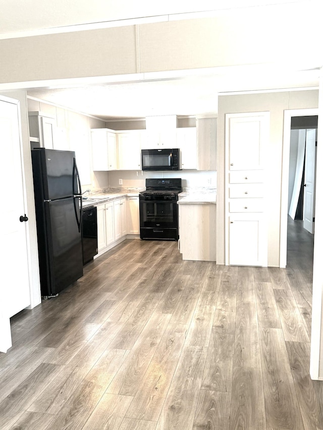 kitchen featuring black appliances, light countertops, light wood-style flooring, and white cabinets