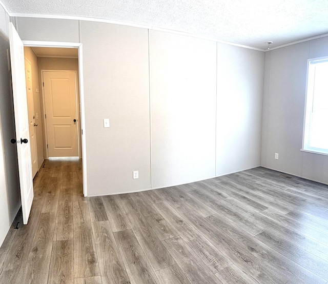 unfurnished bedroom featuring ornamental molding, light wood-style flooring, and a textured ceiling