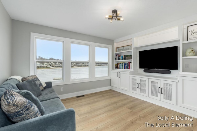 living area featuring built in shelves, visible vents, an inviting chandelier, light wood-style floors, and baseboards