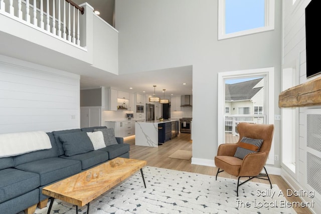 living room with baseboards, a high ceiling, and light wood-style floors