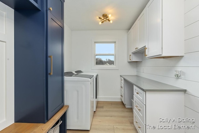 clothes washing area with cabinet space, independent washer and dryer, light wood-style flooring, and baseboards