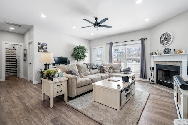 living area with light wood finished floors, visible vents, a ceiling fan, a fireplace with flush hearth, and recessed lighting