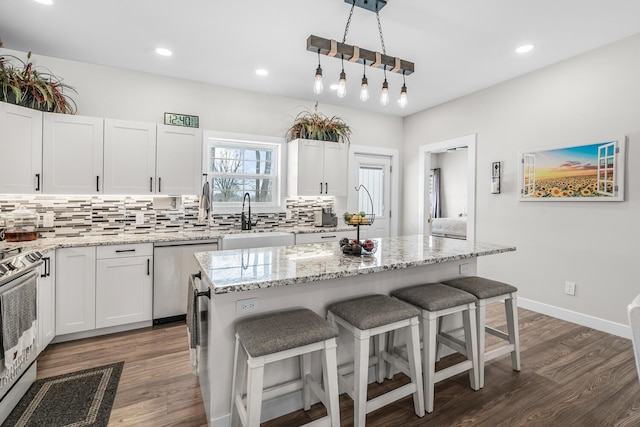 kitchen with dark wood finished floors, a breakfast bar area, backsplash, a sink, and dishwasher