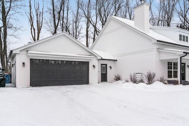 view of snowy exterior featuring a garage and a chimney