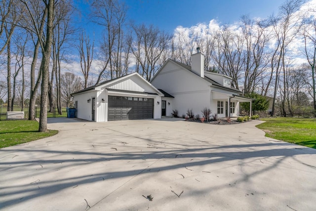 view of side of property with a garage, driveway, and a chimney