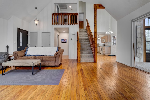 living room featuring high vaulted ceiling, stairway, and hardwood / wood-style flooring