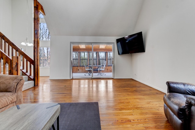 living room with baseboards, stairway, wood finished floors, an inviting chandelier, and high vaulted ceiling