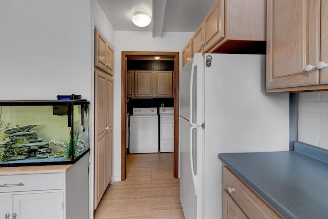 kitchen with tasteful backsplash, washer and clothes dryer, dark countertops, and freestanding refrigerator