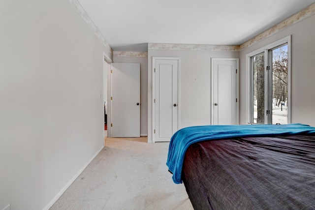 bedroom with access to exterior, carpet, baseboards, and two closets