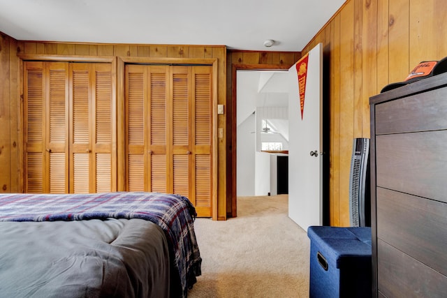 carpeted bedroom with wooden walls and two closets