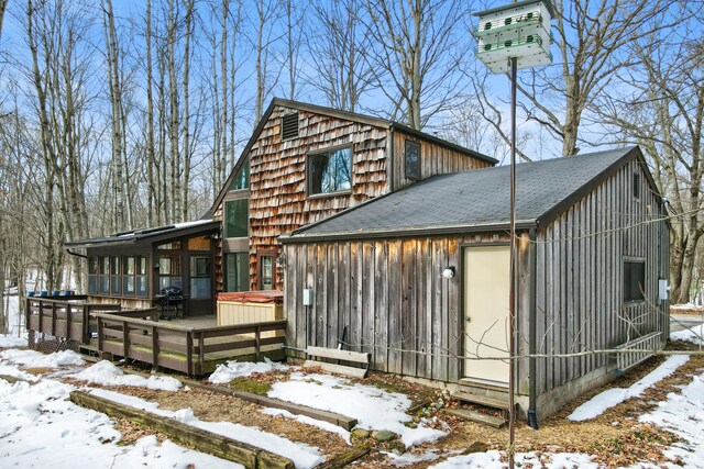 exterior space featuring a shingled roof, board and batten siding, and a wooden deck