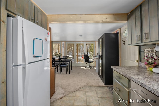 kitchen with light tile patterned flooring, light colored carpet, light countertops, and freestanding refrigerator