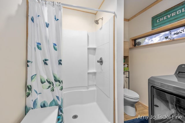 bathroom featuring toilet, a shower with shower curtain, ornamental molding, wood finished floors, and washer / dryer