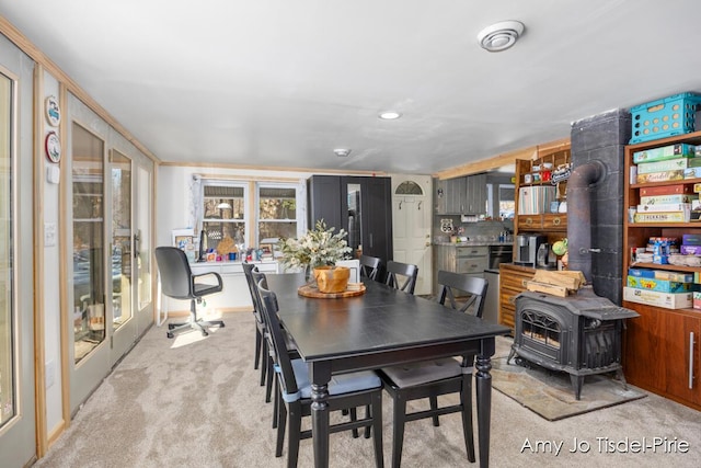 dining room featuring a wood stove and light colored carpet