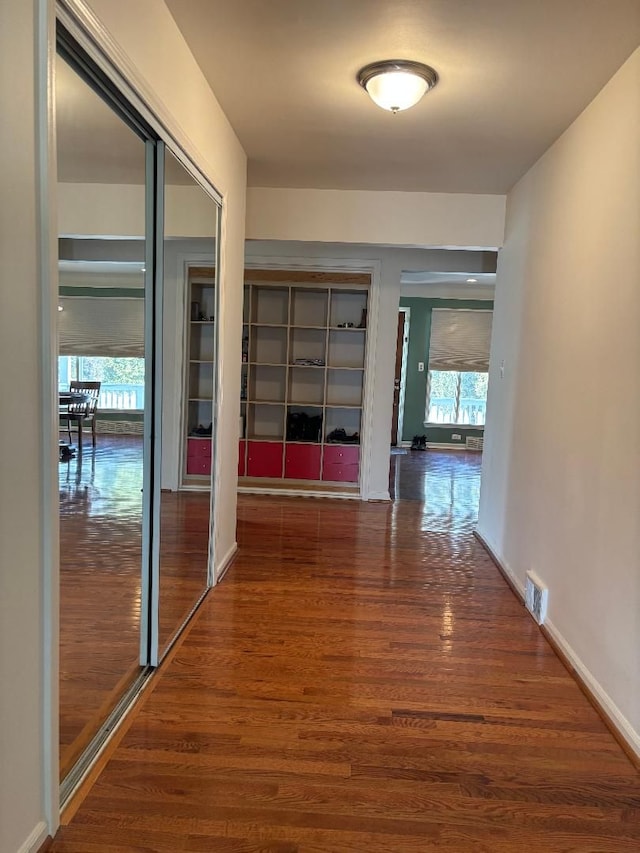 hallway featuring wood finished floors, visible vents, and baseboards