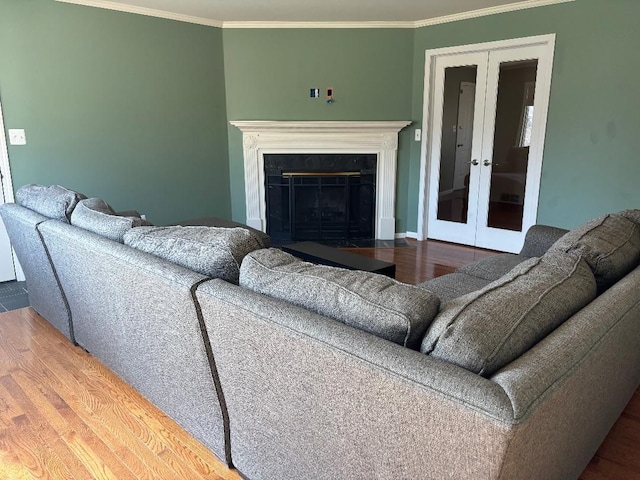 living room featuring a fireplace with flush hearth, french doors, wood finished floors, and crown molding