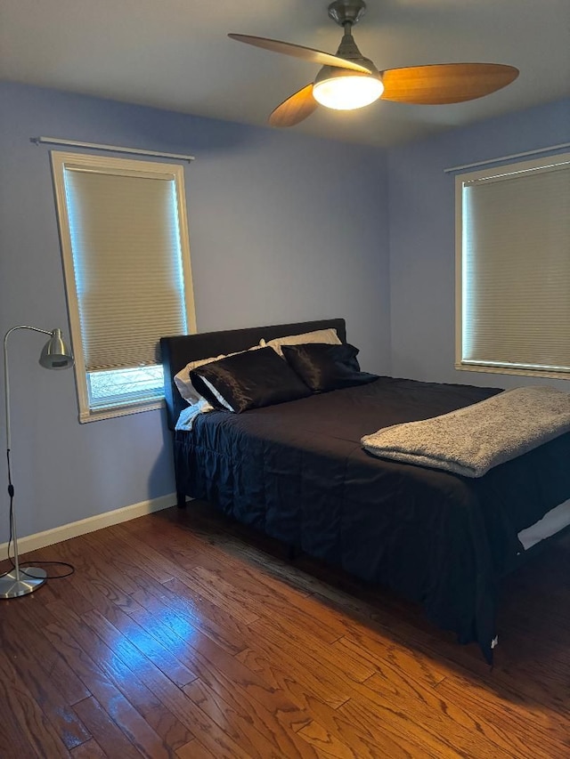 bedroom with a ceiling fan, wood-type flooring, and baseboards