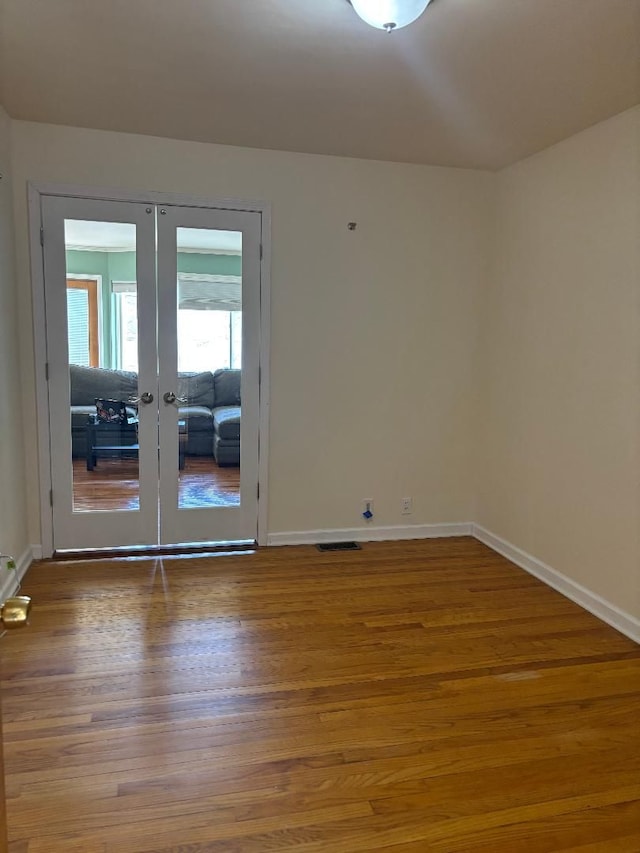 unfurnished room with french doors, visible vents, baseboards, and wood finished floors