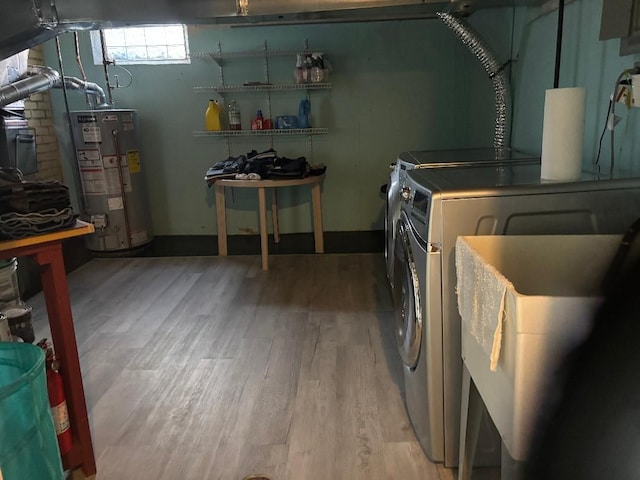 clothes washing area with wood finished floors, laundry area, water heater, and separate washer and dryer