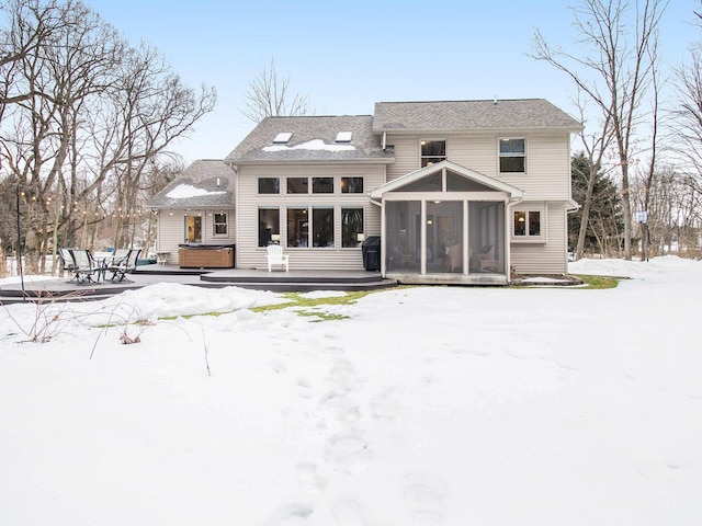 snow covered house with a deck, a sunroom, and a hot tub