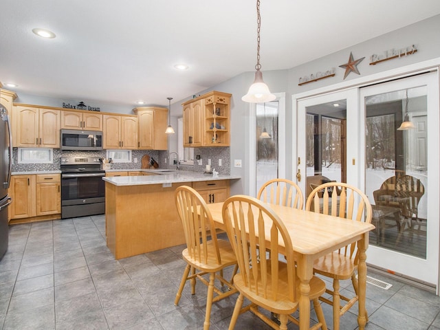 kitchen with appliances with stainless steel finishes, backsplash, a sink, and a peninsula