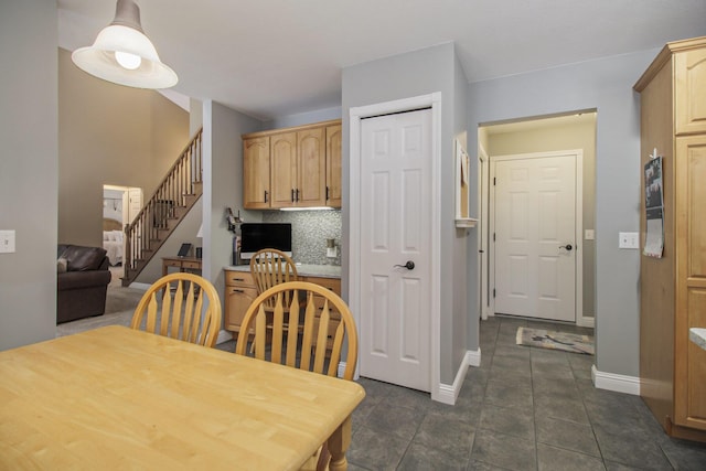 dining room featuring dark tile patterned flooring, stairway, and baseboards