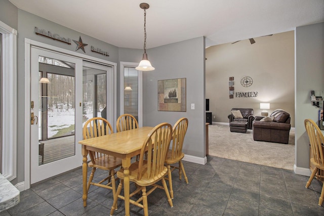 dining space featuring dark colored carpet, a healthy amount of sunlight, and baseboards