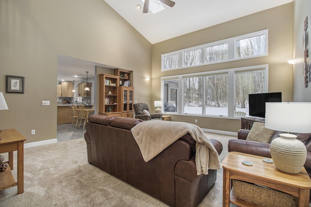 living room with baseboards, high vaulted ceiling, ceiling fan, and light colored carpet