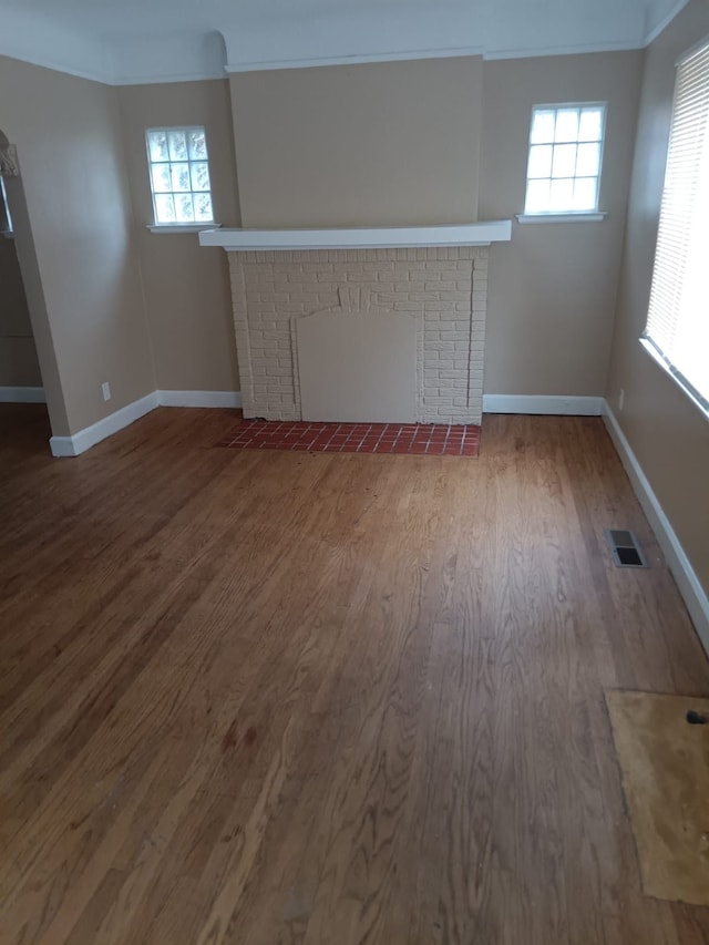 9183 Bishop St, Detroit, MI 48224 - unfurnished living room with plenty of natural light, visible vents, a fireplace, wood finished floors, and baseboards