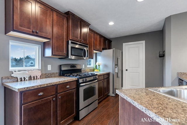 kitchen featuring light countertops, appliances with stainless steel finishes, dark wood-type flooring, a sink, and dark brown cabinets